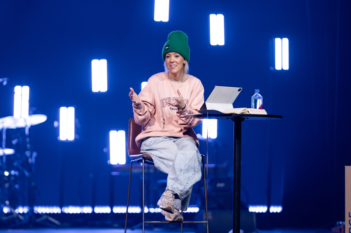 Aynsley teaching under stage lights in a green beanie