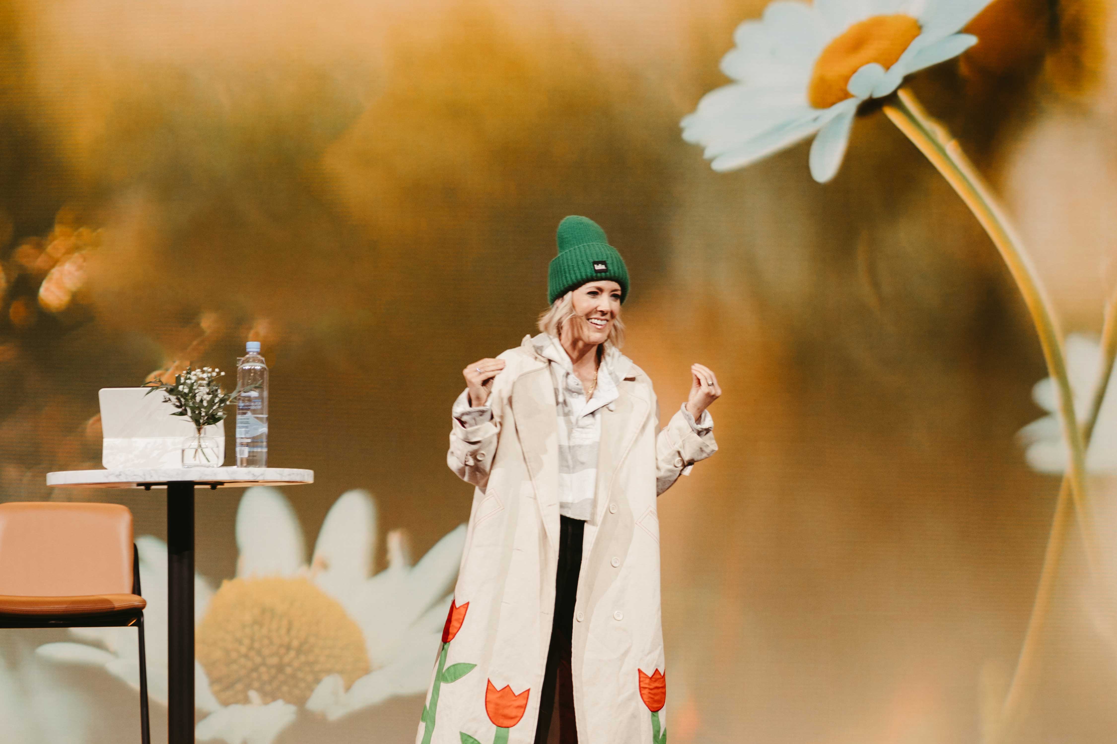 Aynsley teaching on stage in a tulip-printed coat