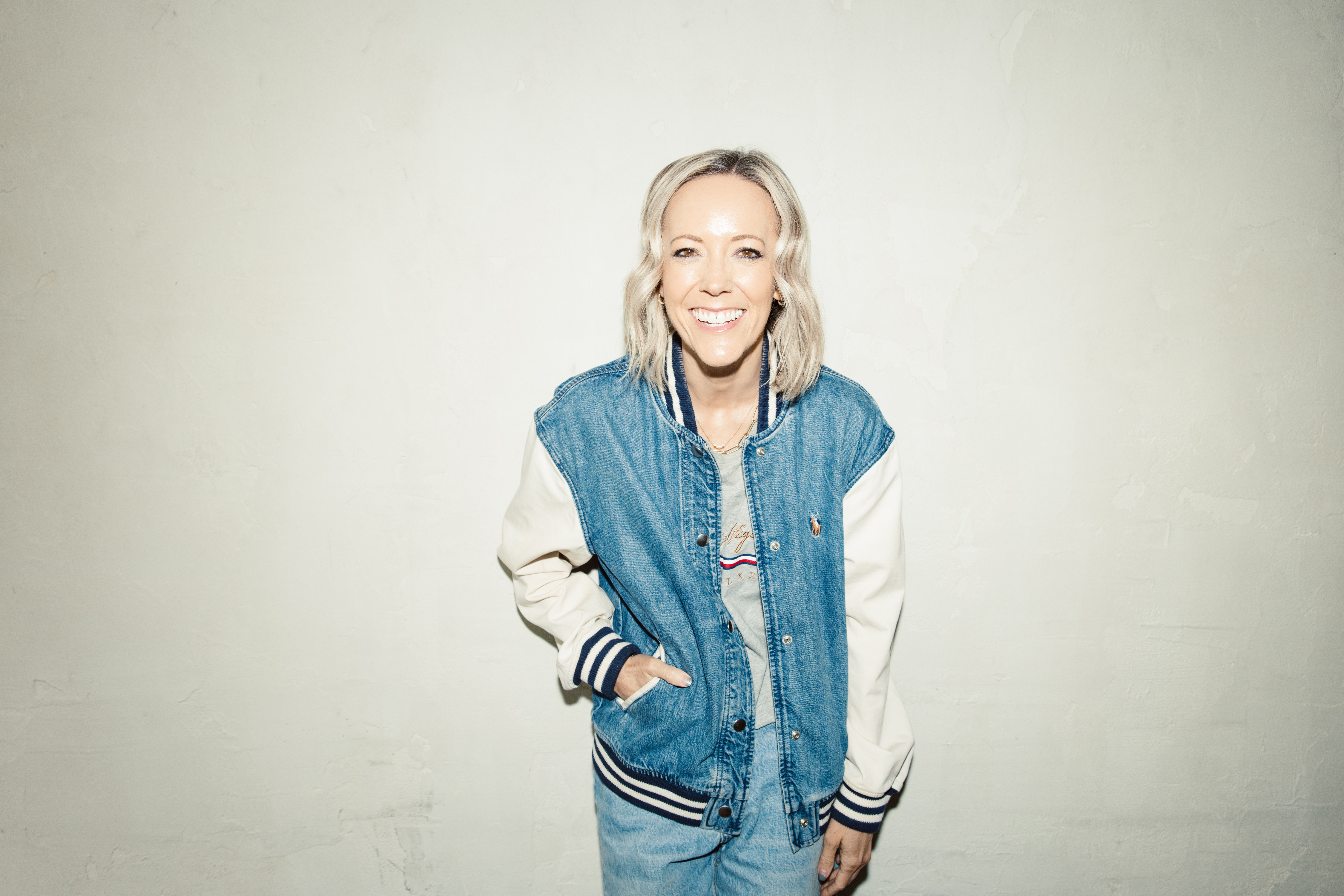 Portrait of Aynsley Younker, smiling, wearing a denim varsity jacket